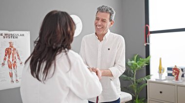 Kıdemli erkek ve kadın doktor ve hasta klinikte tıbbi danışmanlık yapıyorlar.