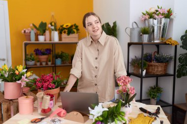 Çiçekçi dükkanında kendine gülen beyaz bir kadın.