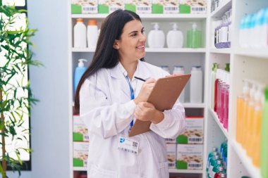 Genç, güzel İspanyol kadın eczacı eczanedeki belgeye yazı yazıyor.