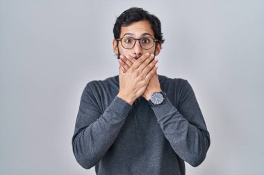 Tecrit edilmiş arka planda duran yakışıklı latin adam yanlışlıkla elleriyle ağzını kapatmış. gizli kavram. 