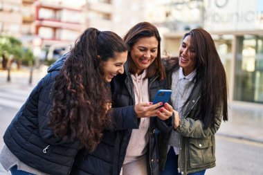 Sokakta akıllı telefon kullanan üç kadın anne ve kız.