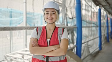 Güzel İspanyol kadın mimar gülümsüyor. Kollarını kavuşturup caddede duruyor.