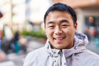 Young chinese man smiling confident standing at street