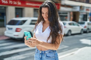 Sokakta akıllı telefon kullanan, kendine güvenen genç İspanyol kadın.