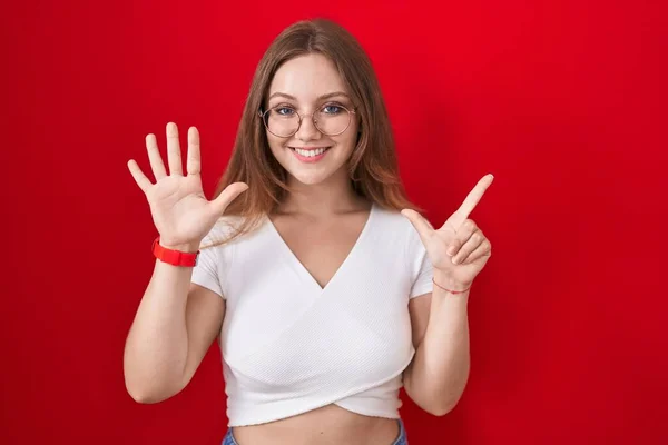 Mladá Běloška Stojící Nad Červeným Pozadím Ukazující Ukazující Prsty Číslo — Stock fotografie