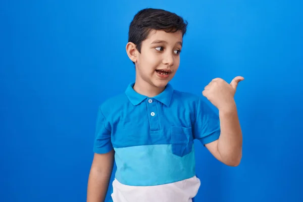 Küçük Spanyol Çocuk Mavi Arka Planda Dikiliyor Başparmağını Yana Kaldırıyor — Stok fotoğraf