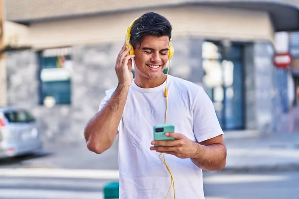 ストリートで音楽を聞いて自信を持って笑っている若いヒスパニック系の男 — ストック写真