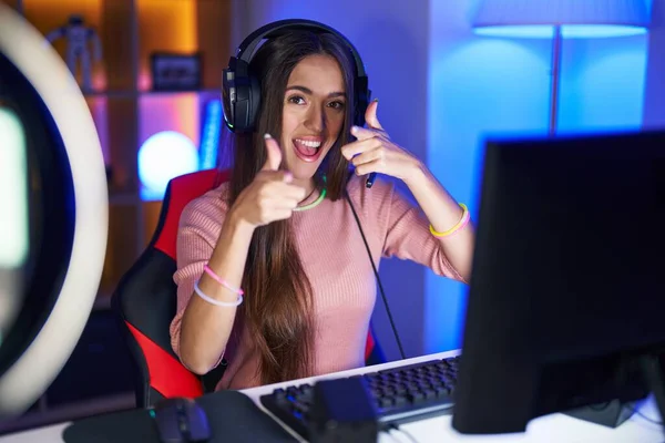 Video oyunları oynayan genç İspanyol kadın mutlu ve komik yüzüyle kamerayı işaret ediyor. iyi enerji ve titreşimler. 