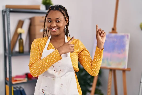 アフリカ系アメリカ人の女性は アートスタジオで 両手と指を横に向けてカメラを見て笑っています — ストック写真