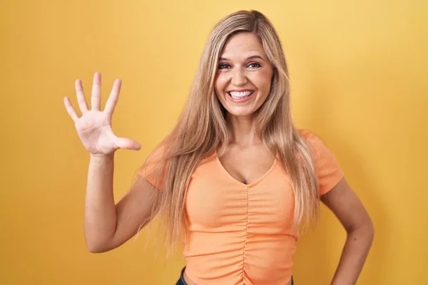 Молодая Женщина Стоит Желтом Фоне Показывая Указывая Пальцами Номер Пять — стоковое фото