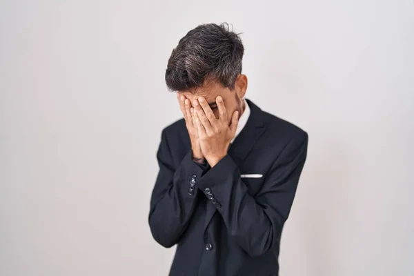 ビジネススーツを着た入れ墨をした若いヒスパニック系の男と泣きながら手で顔を覆う悲しい表情でネクタイ うつ病の概念 — ストック写真