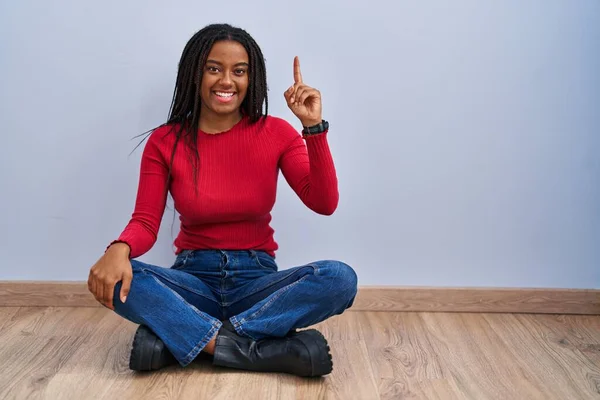 Joven Afroamericano Con Trenzas Sentado Suelo Casa Señalando Con Dedo —  Fotos de Stock