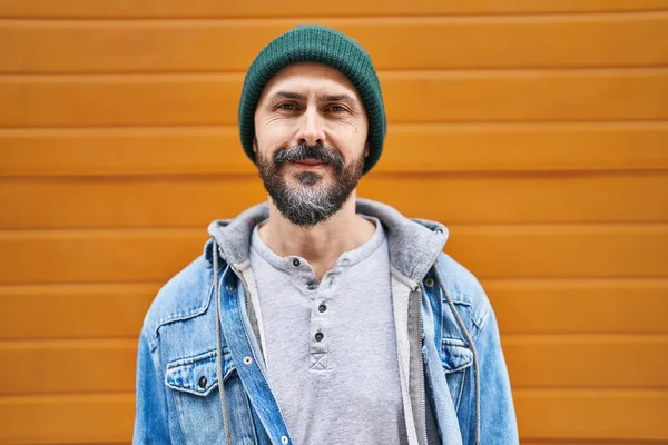 Genç kel adam gülerek izole ahşap arka planda duruyor.