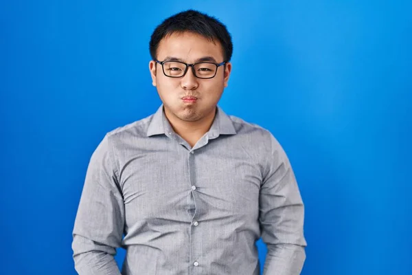 Mladý Číňan Který Stojí Nad Modrým Pozadím Nadouvá Tváře Legračním — Stock fotografie