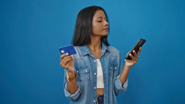 用智能手机和信用卡在孤立的蓝色背景下购物的非裔美国妇女 — 图库照片