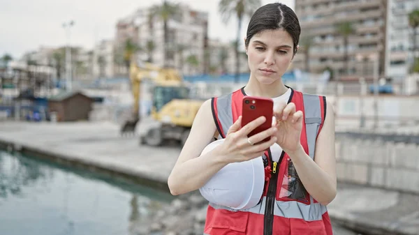 Mladá Krásná Hispánská Žena Stavitel Pomocí Smartphone Držení Hardhat Moře — Stock fotografie
