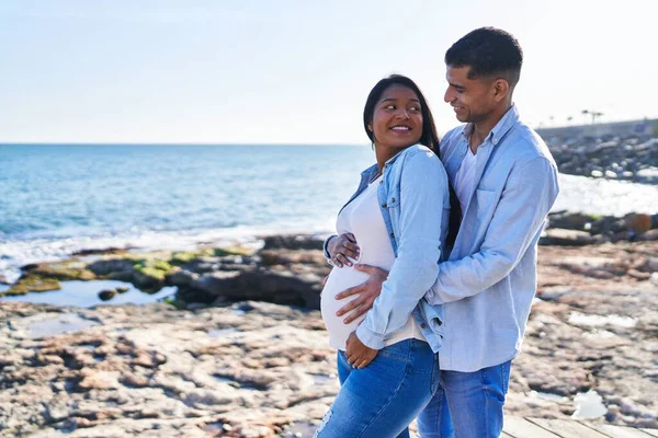 Young Latin Couple Expecting Baby Hugging Each Other Standing Seaside — Stockfoto