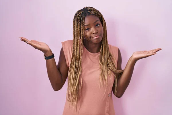 Африканская Американка Плетеными Волосами Стоящая Розовом Фоне Невежественное Запутанное Выражение — стоковое фото
