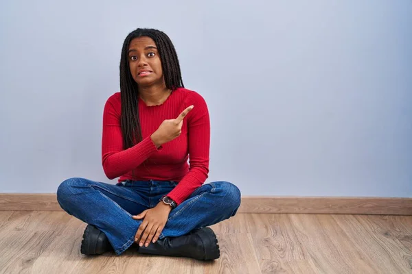 Joven Afroamericano Con Trenzas Sentado Suelo Casa Señalando Lado Preocupado —  Fotos de Stock