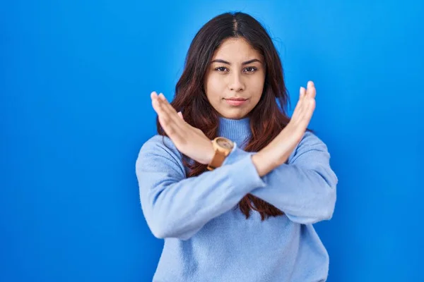 西班牙裔年轻女子站在蓝色的背景上拒绝的表情交叉双臂做着消极的手势 生气的脸 — 图库照片