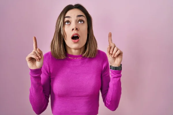 Hispanic Woman Standing Pink Background Amazed Surprised Looking Pointing Fingers — Foto Stock