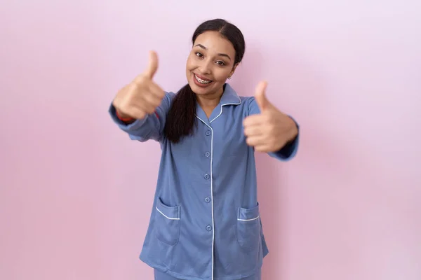 stock image Young arab woman wearing blue pajama approving doing positive gesture with hand, thumbs up smiling and happy for success. winner gesture. 