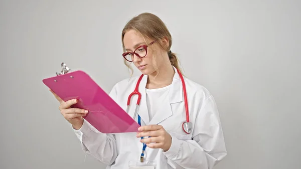 年轻的金发女医生在剪贴板上阅读文件 而不是孤立的白色背景 — 图库照片