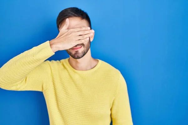 Hispanic Man Standing Blue Background Covering Eyes Hand Looking Serious — Stok fotoğraf