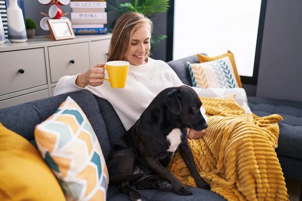 Νεαρή Ξανθιά Γυναίκα Πίνοντας Καφέ Κάθεται Στον Καναπέ Σκυλί Στο — Φωτογραφία Αρχείου