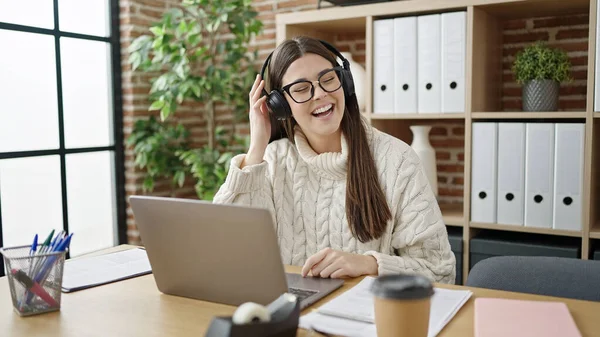 オフィスで働くラップトップとヘッドフォンを使用して若い美しいヒスパニック系女性のビジネスワーカー — ストック写真