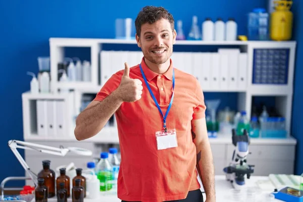 Young Hispanic Man Working Scientist Laboratory Doing Happy Thumbs Gesture — Stock Photo, Image