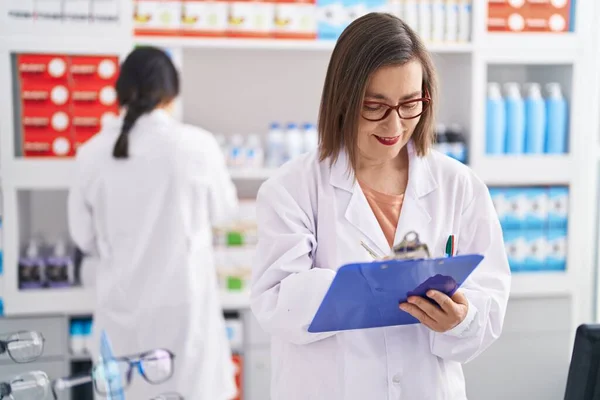 Two Women Pharmacist Smiling Confident Writing Document Pharmacy — Zdjęcie stockowe