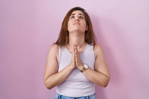 Bruneta Žena Stojí Nad Růžovým Pozadím Žebrající Modlící Rukama Spolu — Stock fotografie