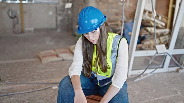 年轻美丽的惊慌失措的女建筑工人疲惫地坐在建筑工地上 — 图库照片