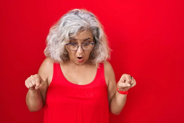 Kırmızı Arka Planda Gri Saçlı Orta Yaşlı Bir Kadın Parmaklarını — Stok fotoğraf