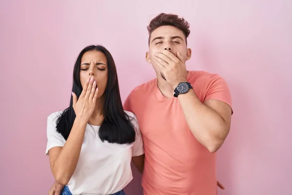 Young Hispanic Couple Standing Pink Background Bored Yawning Tired Covering — Foto Stock