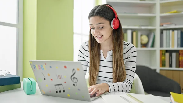 図書館大学で勉強しているラップトップとヘッドフォンを使用して若い美しいヒスパニック女性の学生 — ストック写真