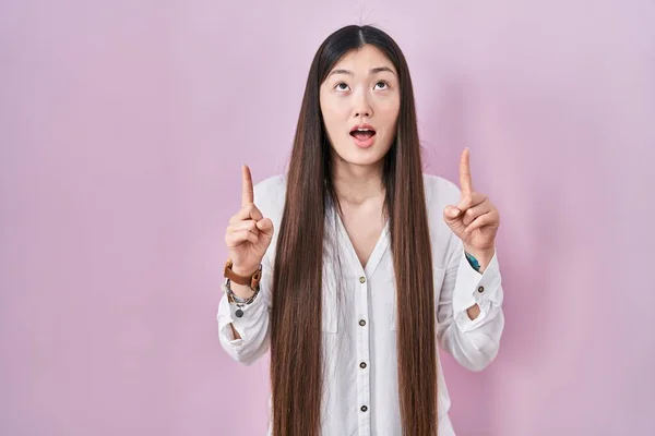 Chinese Young Woman Standing Pink Background Amazed Surprised Looking Pointing — 图库照片