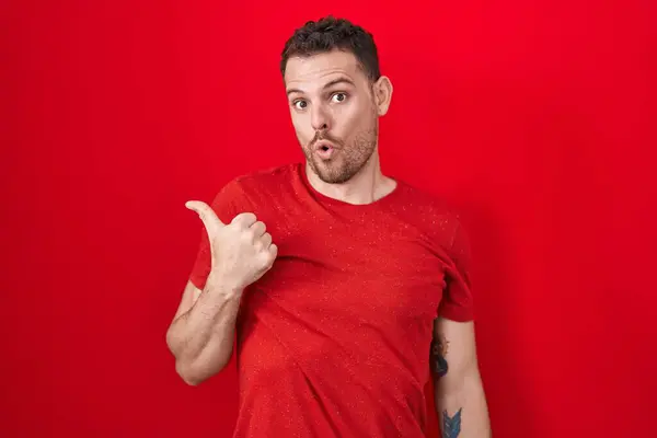 Young Hispanic Man Standing Red Background Surprised Pointing Hand Finger — Stock Photo, Image