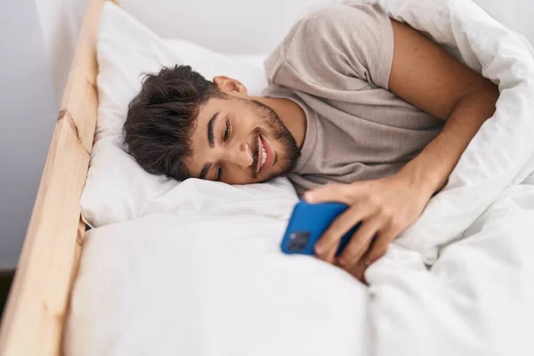 Young Arab Man Using Smartphone Lying Bed Bedroom — Stok fotoğraf