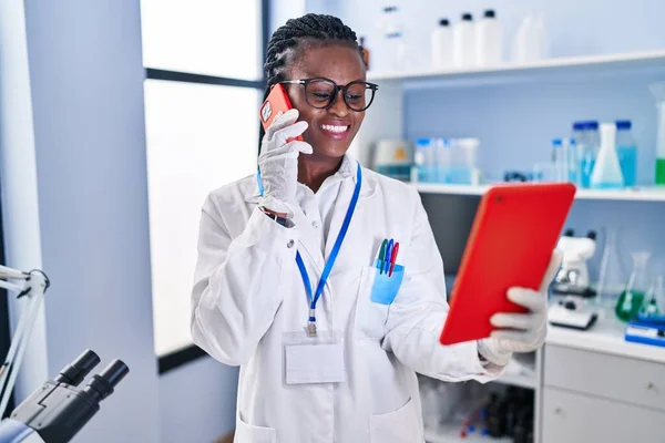 アフリカ系アメリカ人女性科学者が研究室でタッチパッドを使ってスマートフォンで話す — ストック写真