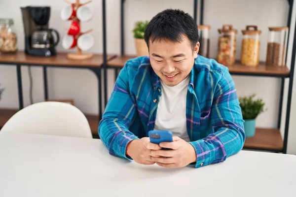 Young Chinese Man Using Smartphone Sitting Table Home —  Fotos de Stock