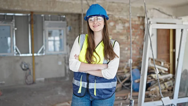 惊慌失措的女建筑工人微笑着 自信地站在建筑工地上 双手交叉地做着手势 — 图库照片