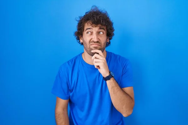 Hispánský Mladý Muž Stojící Nad Modrým Pozadím Přemýšlející Otázce Znepokojený — Stock fotografie