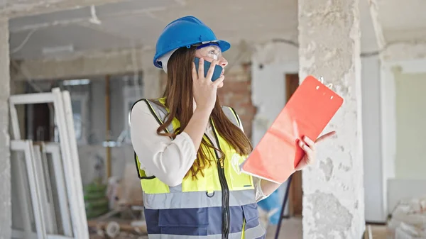 年轻美丽的惊慌失措的女建筑商在建筑工地用智能手机阅读文档 — 图库照片