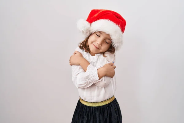 Μικρό Ισπανόφωνο Κορίτσι Που Φοράει Χριστουγεννιάτικο Καπέλο Αγκαλιάζοντας Τον Εαυτό — Φωτογραφία Αρχείου