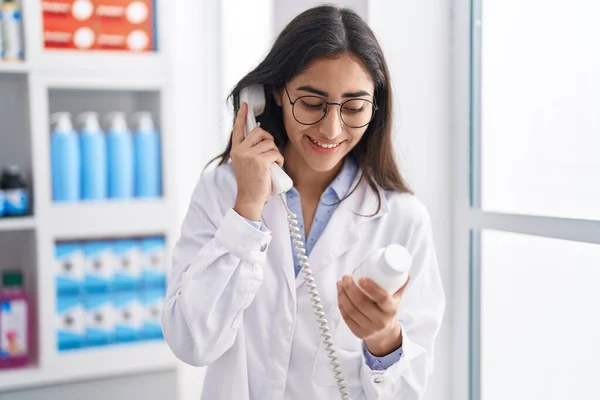 Young Hispanic Girl Pharmacist Talking Telephone Holding Pills Pharmacy — Stockfoto