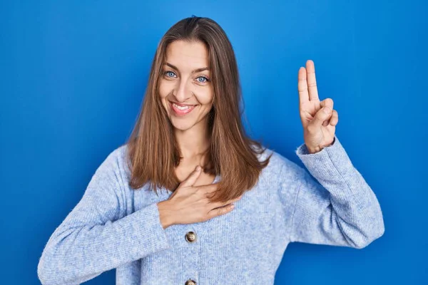 Young Woman Standing Blue Background Smiling Swearing Hand Chest Fingers — Zdjęcie stockowe