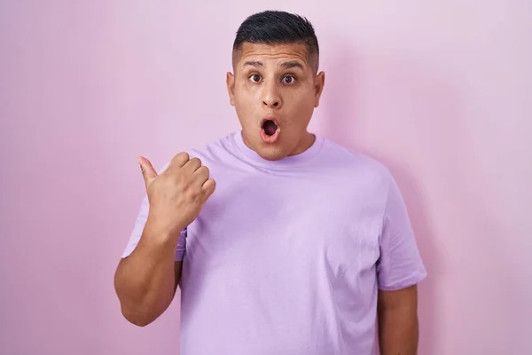 Young Hispanic Man Standing Pink Background Surprised Pointing Hand Finger — Stok fotoğraf