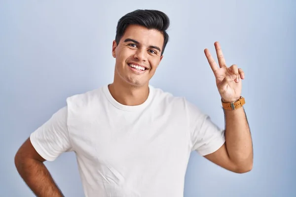 Hispanic Man Standing Blue Background Smiling Looking Camera Showing Fingers — Stok fotoğraf